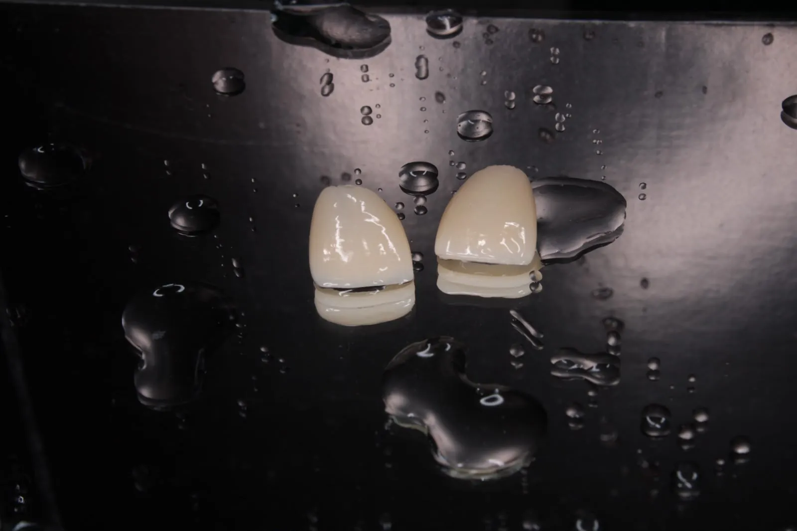 Dos carillas de cerámica con gotas de agua sobre fondo negro