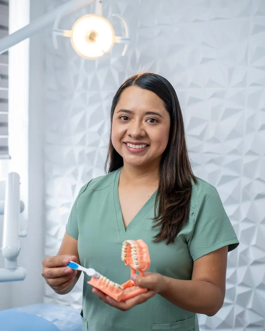 Dra. Guadalupe Juárez Martínez en su consultorio, con un modelo dental